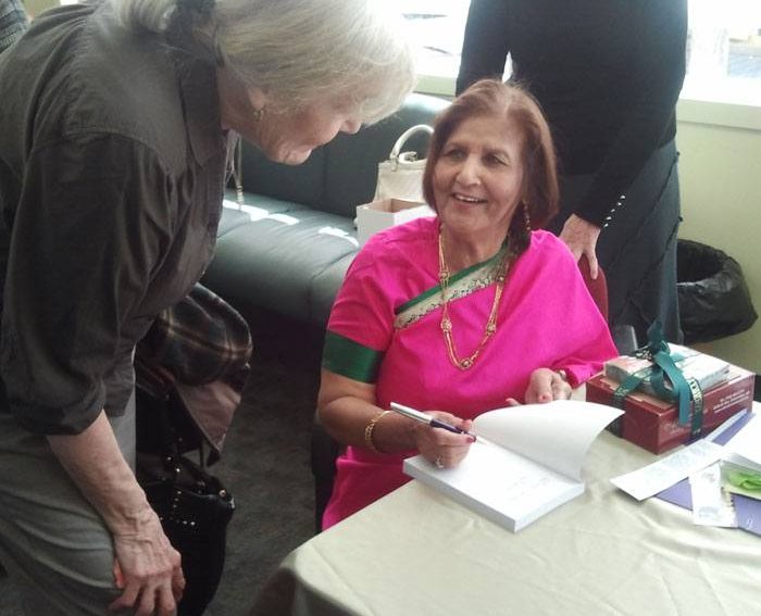 Shashi in sari signing a copy of her book